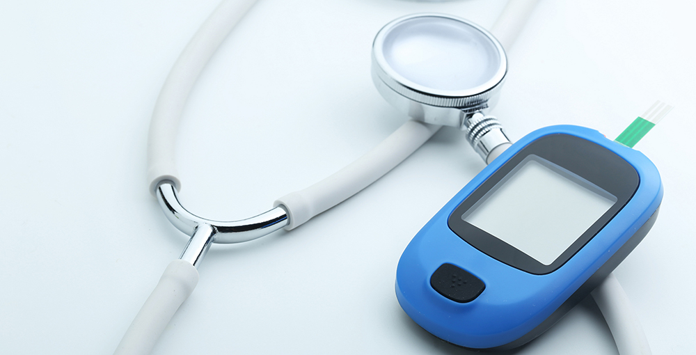 Blood glucose meter and stethoscope on white background